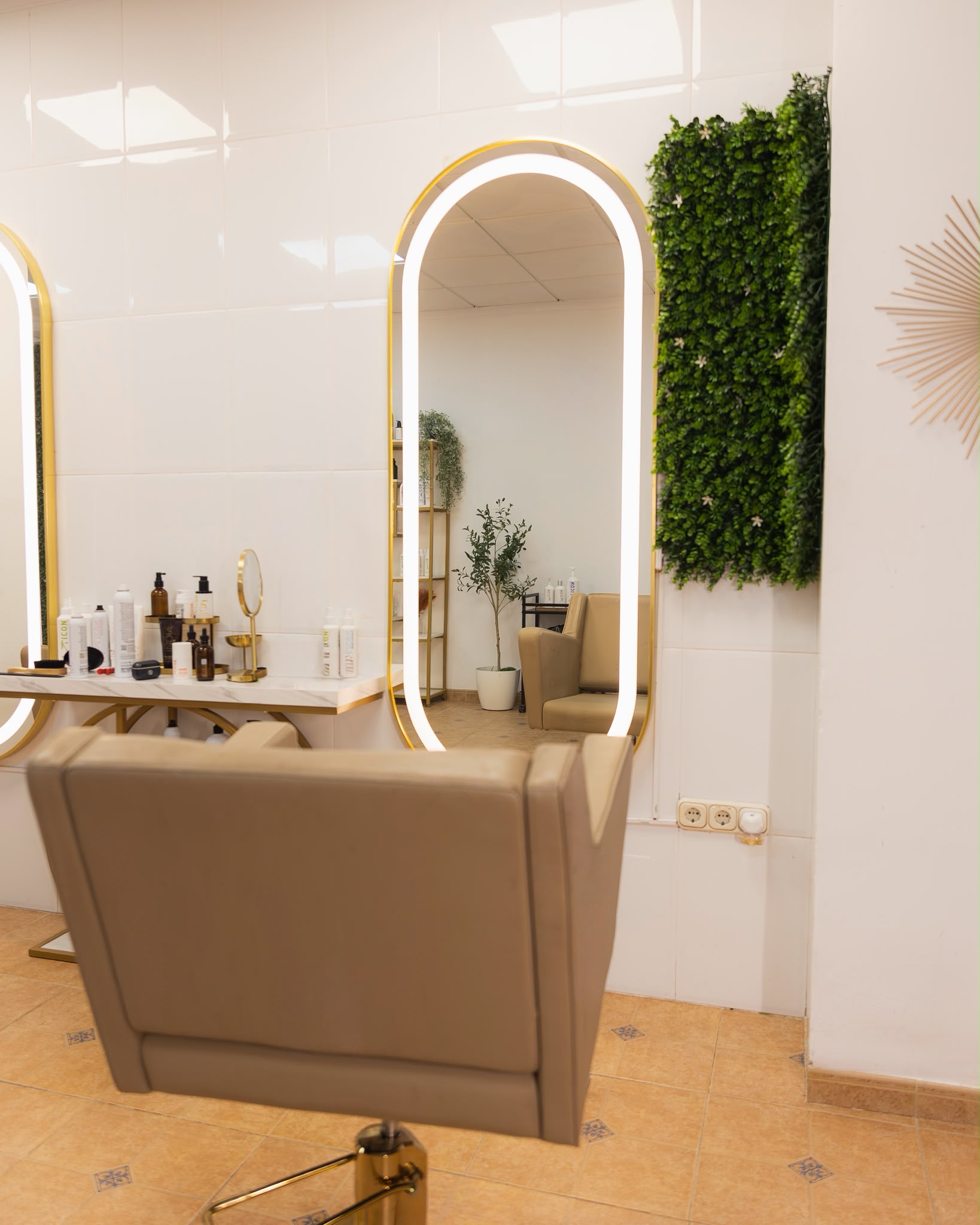 Interior de Sergio Torres Salon en El Ejido: tocador con espejo iluminado en dorado y jardín vertical