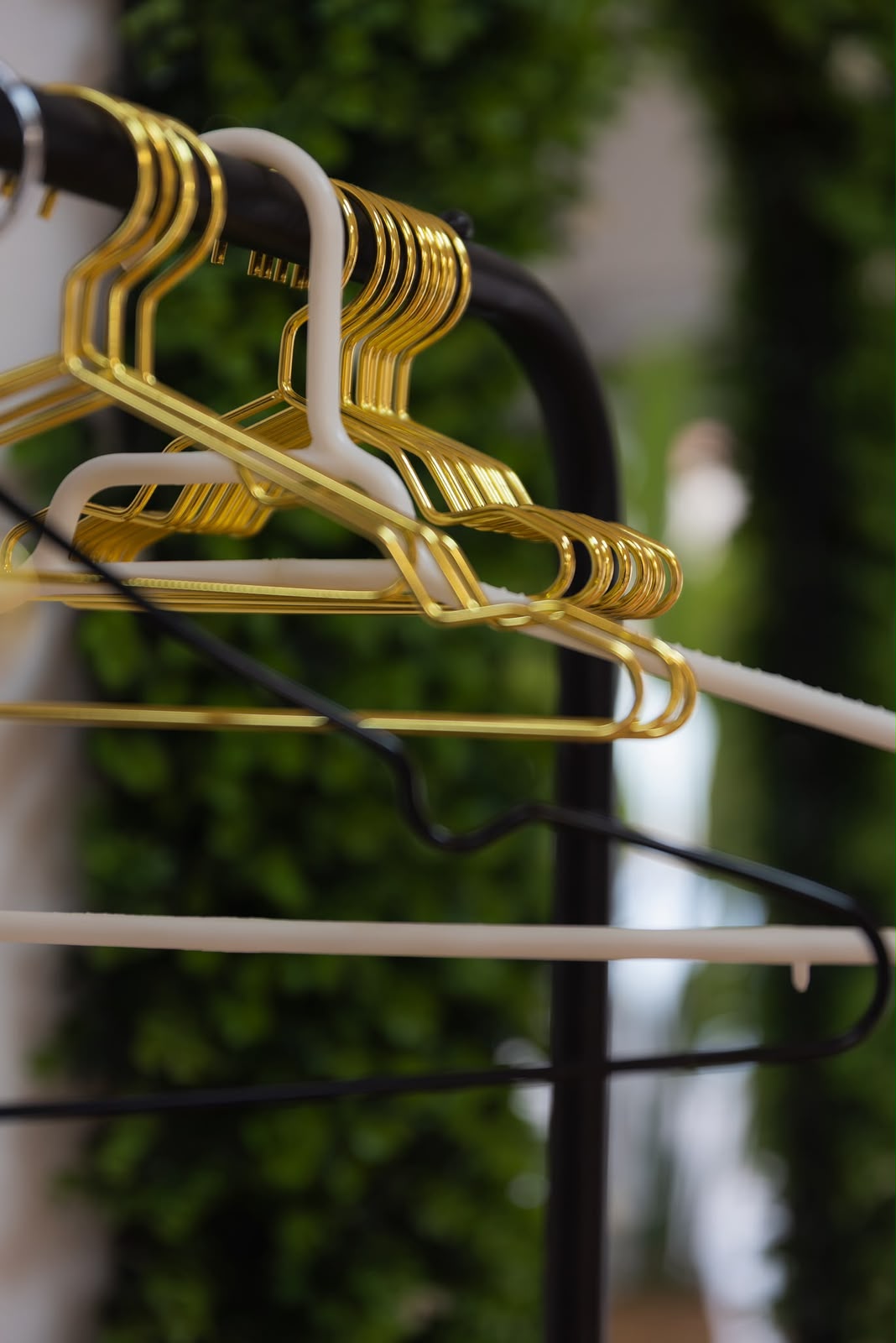 Perchas doradas en el salón, con el jardín vertical de fondo